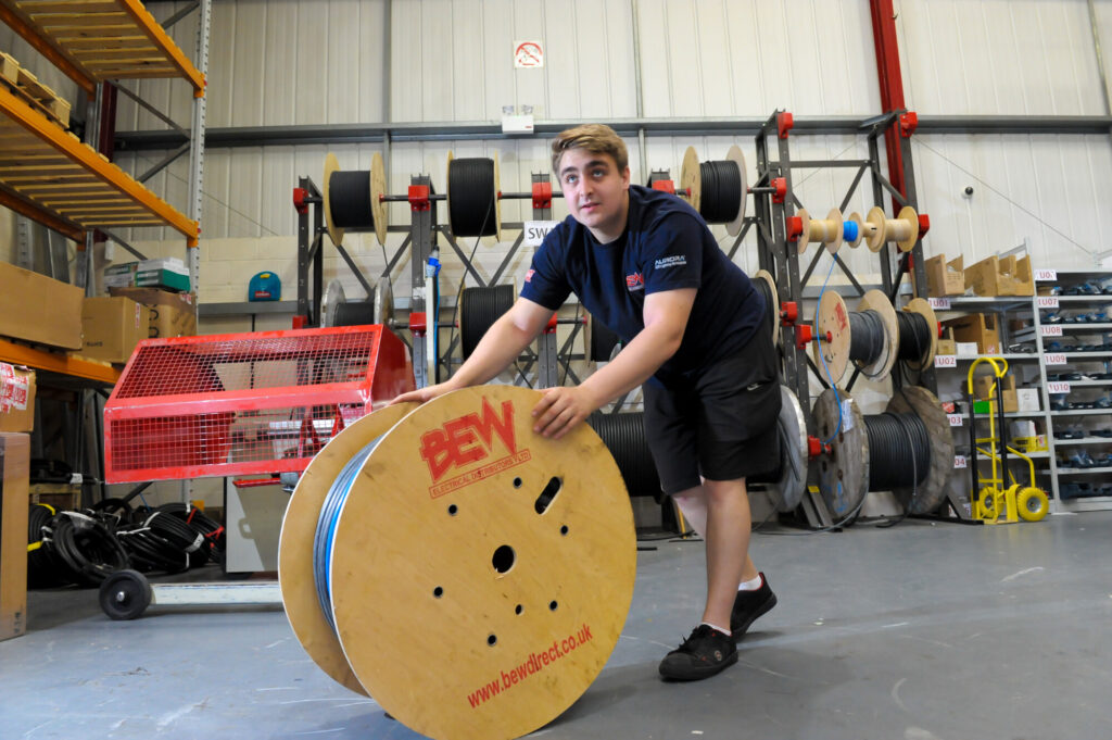 BEW Electrical Guildford warehouse member rolling a spool of electrical cable